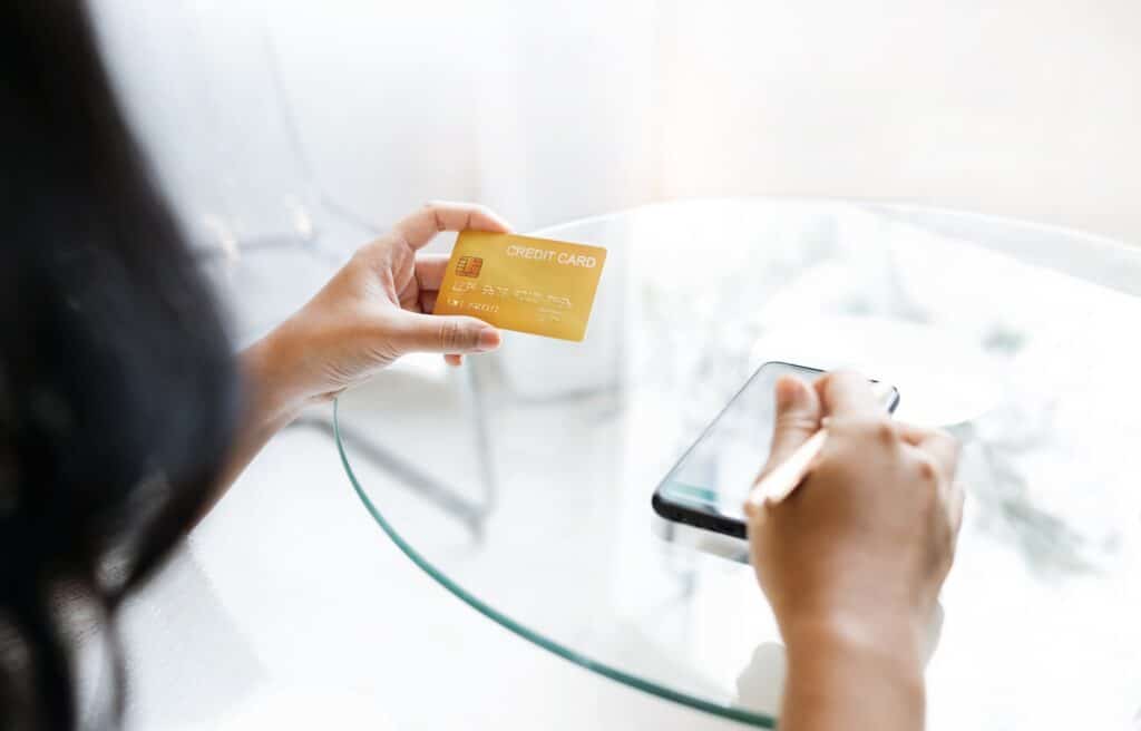 Une femme regarde sa carte bancaire gold assise à une table