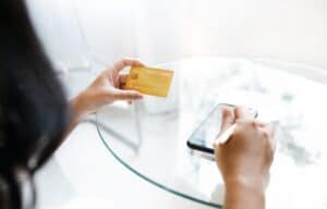 Une femme regarde sa carte bancaire gold assise à une table
