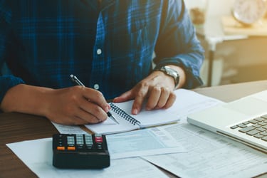 Un homme à un bureau qui utilise sa calculatrice