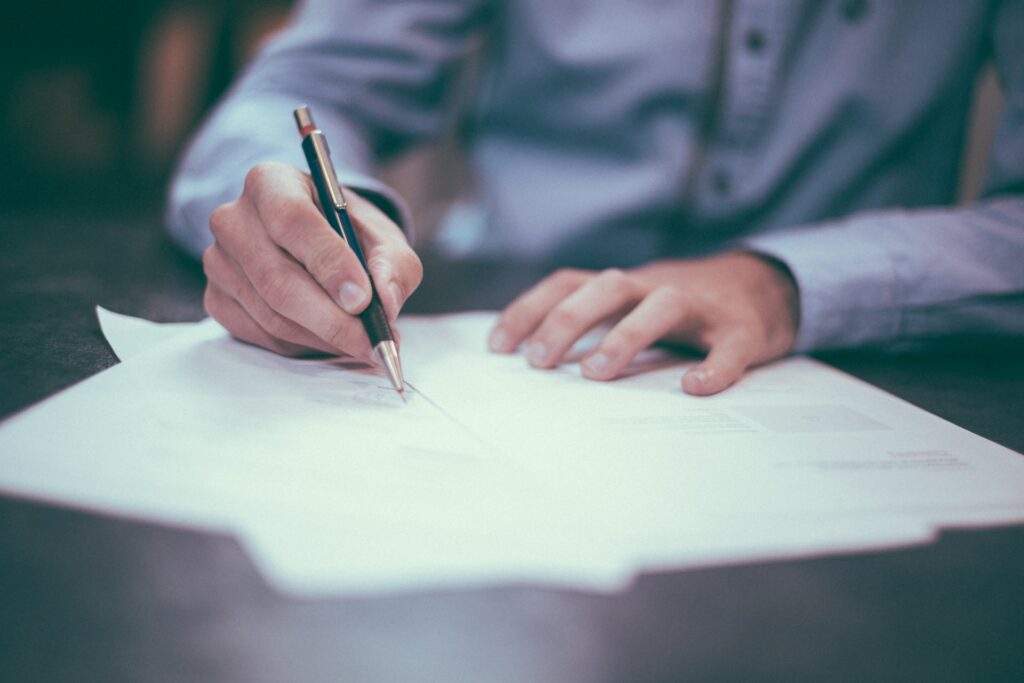 Un homme assis à une table qui signe un papier