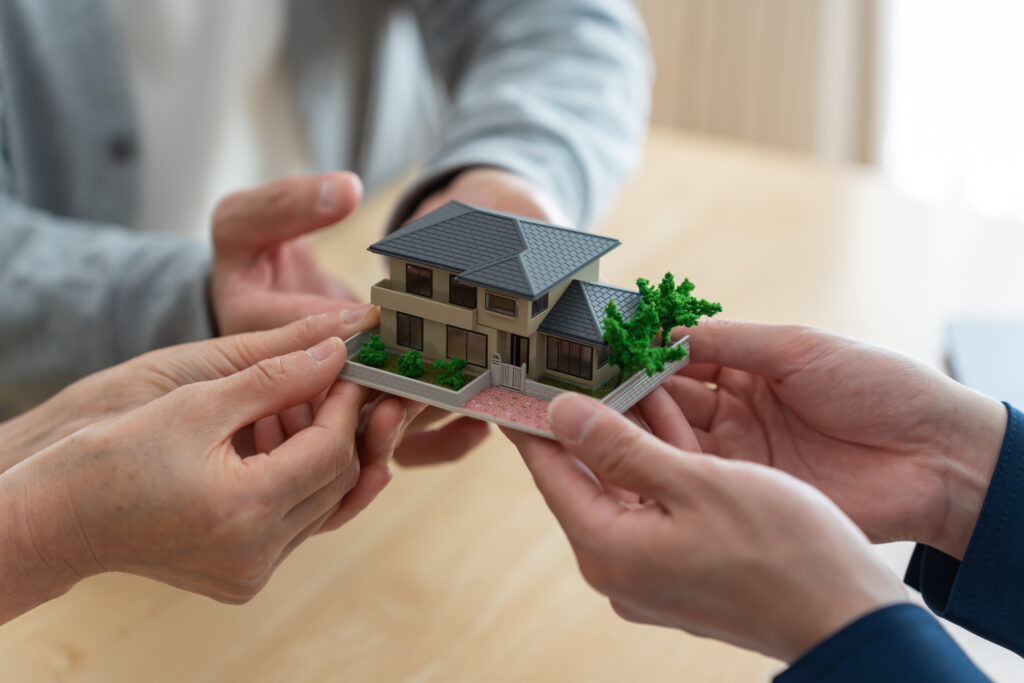 Des mains tiennent une maquette d'une maison