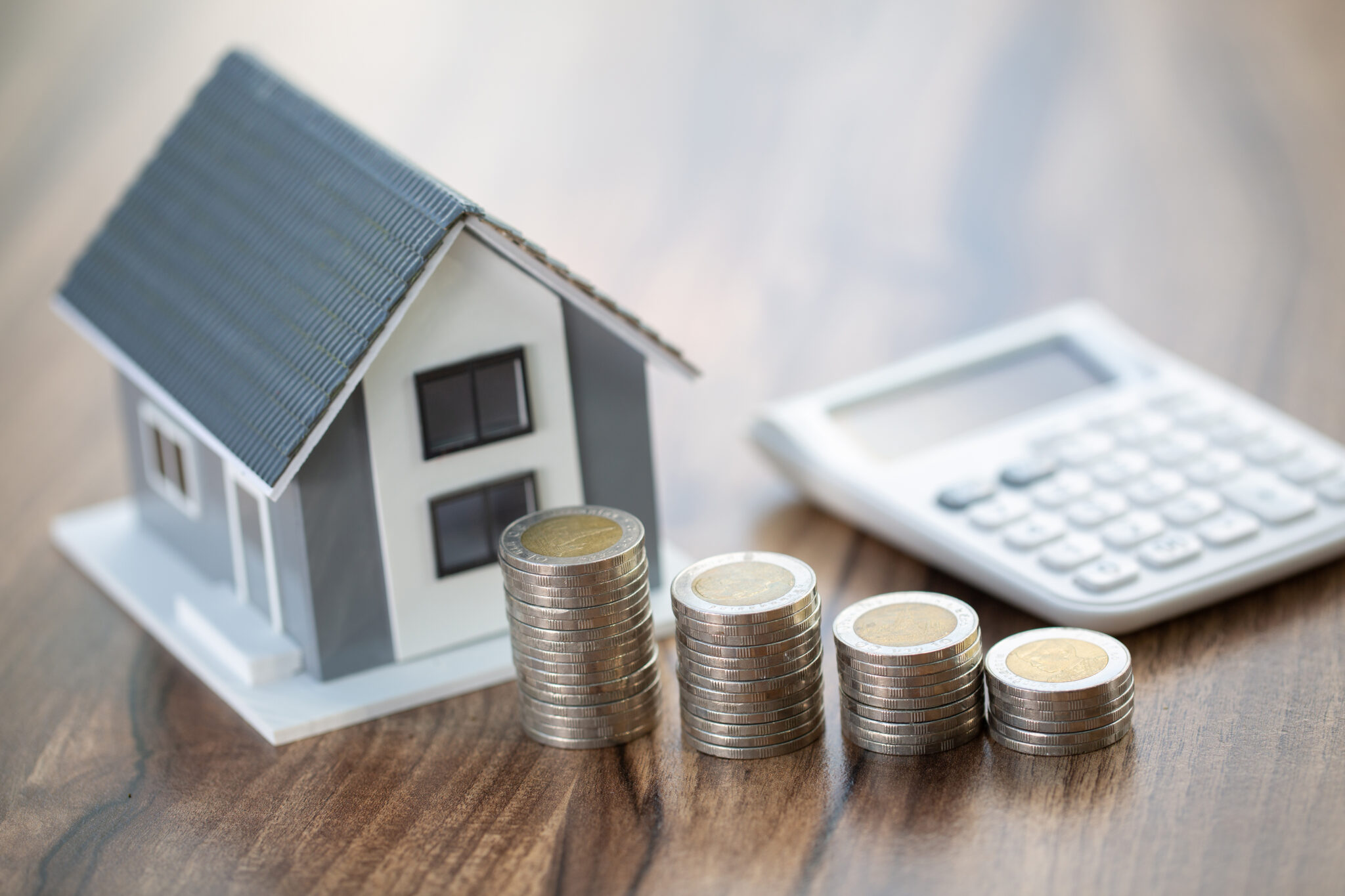 Maquette d'une maison, d'une calculatrice et de pièces posés sur une table 