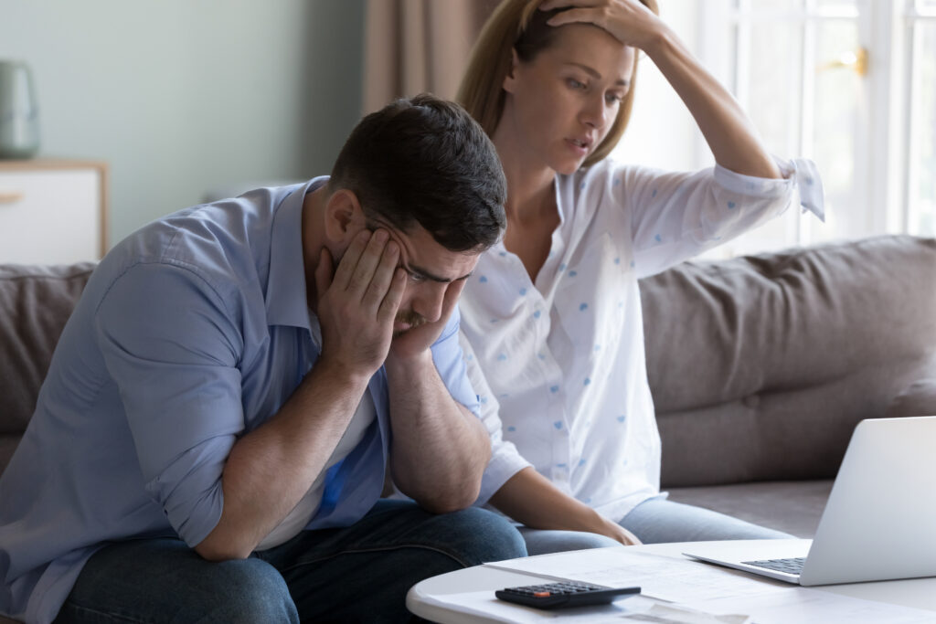 Un couple assis sur un canapé entrain de faire les comptes